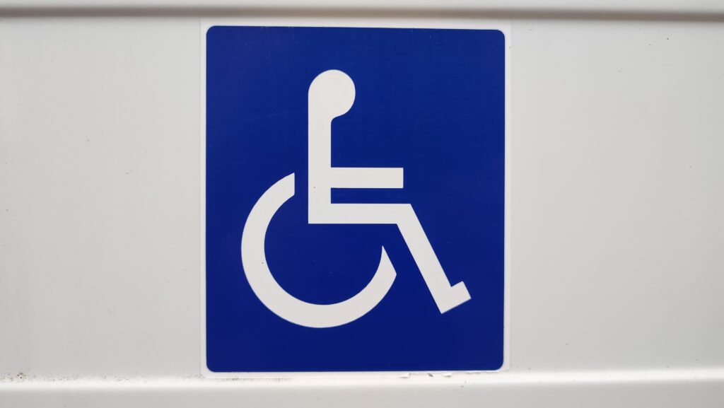 Simbolo disabilità con omino stilizzato su carrozzina su sfondo blu
