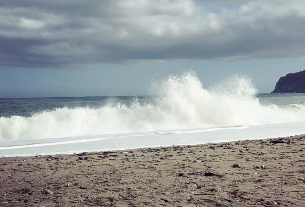 Spiaggia con mare: onde alte che si rompono sulla sabbia