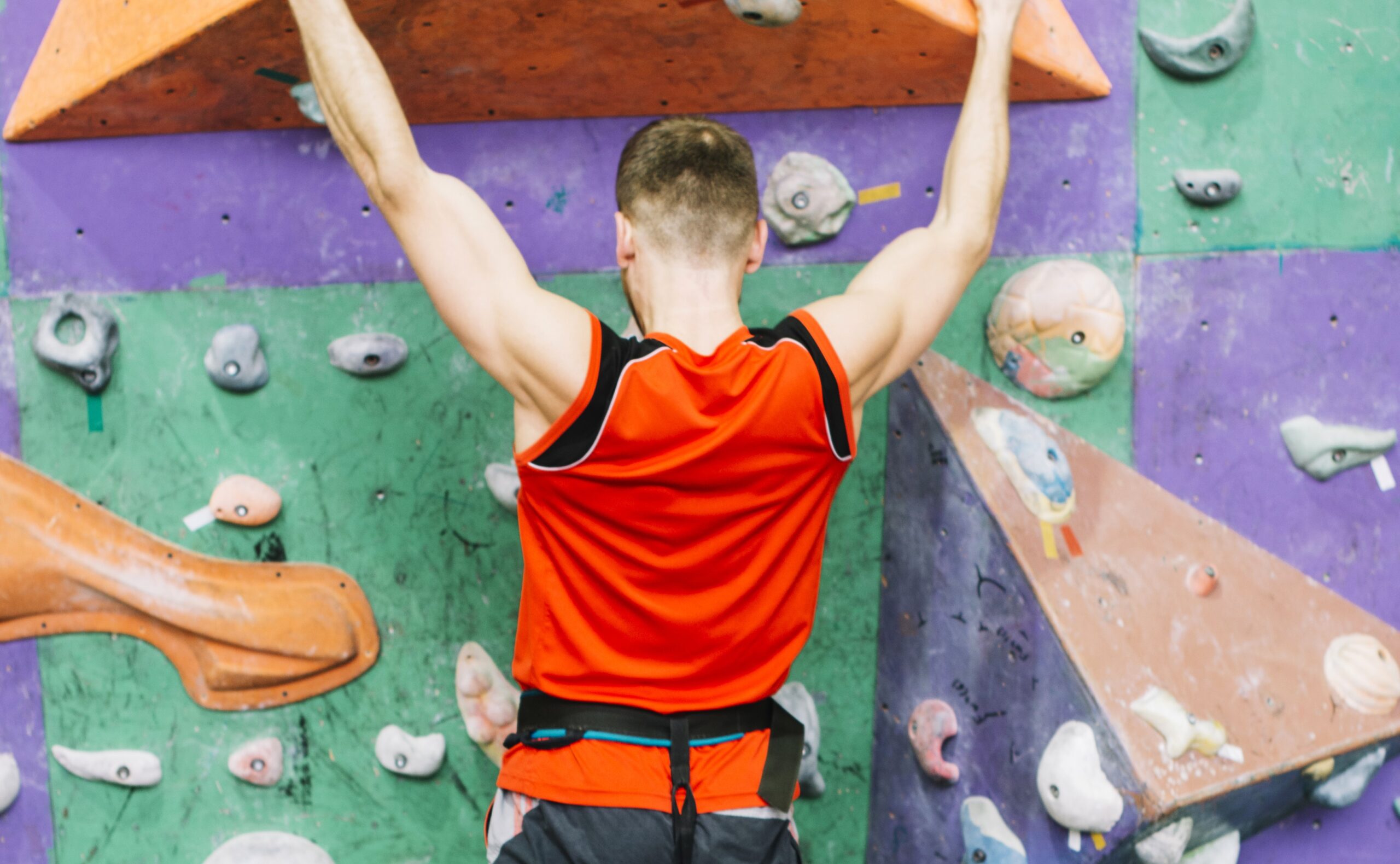 Uomo mentre pratica l'arrampicata sportiva paralimpica, aggrappato a una parete artificiale